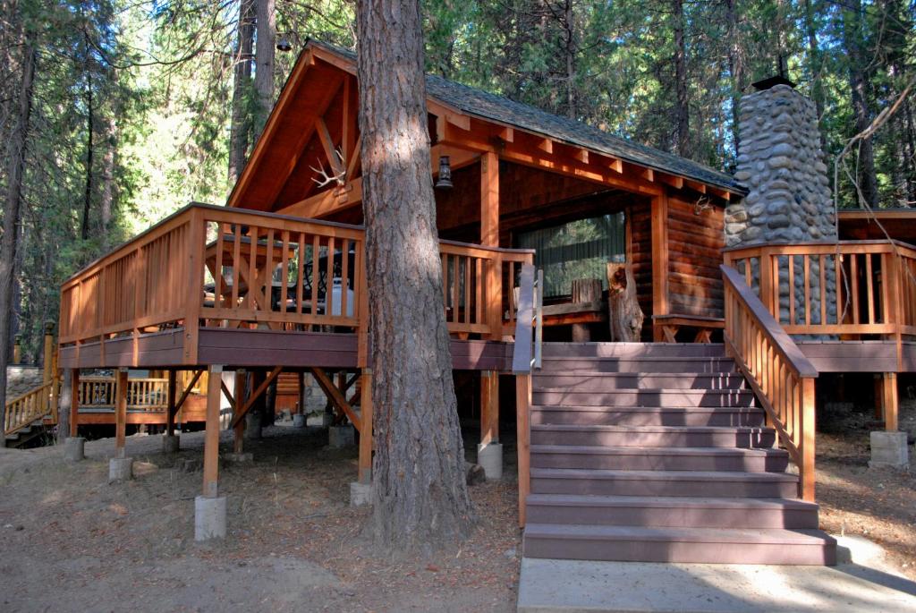 a log cabin in the woods with stairs and a tree at 26 Deer Den in North Wawona