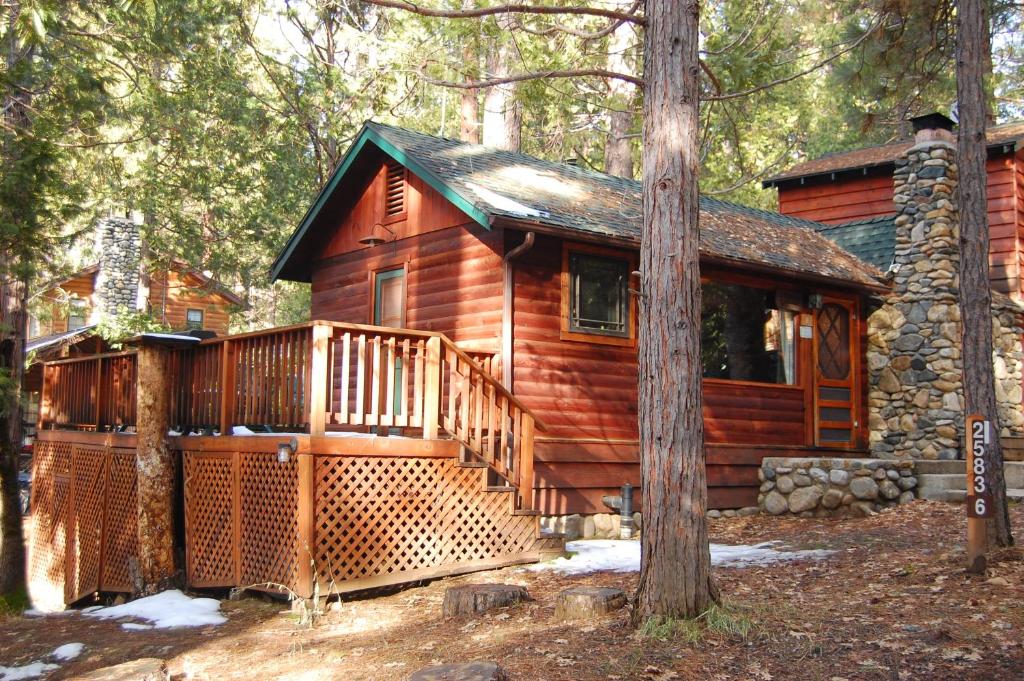 a log cabin with a large deck in the woods at 6 Squirrels Nest in Wawona