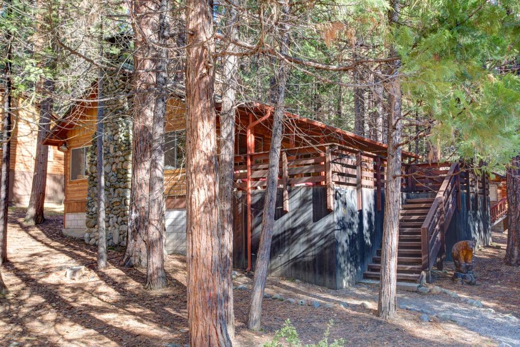 a cabin in the woods with a dog in front of it at 70 Simmons Den in Wawona