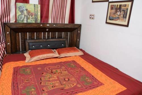 Karina art Home stay في بيكانير: غرفة نوم بسرير وبطانية حمراء وبرتقالية