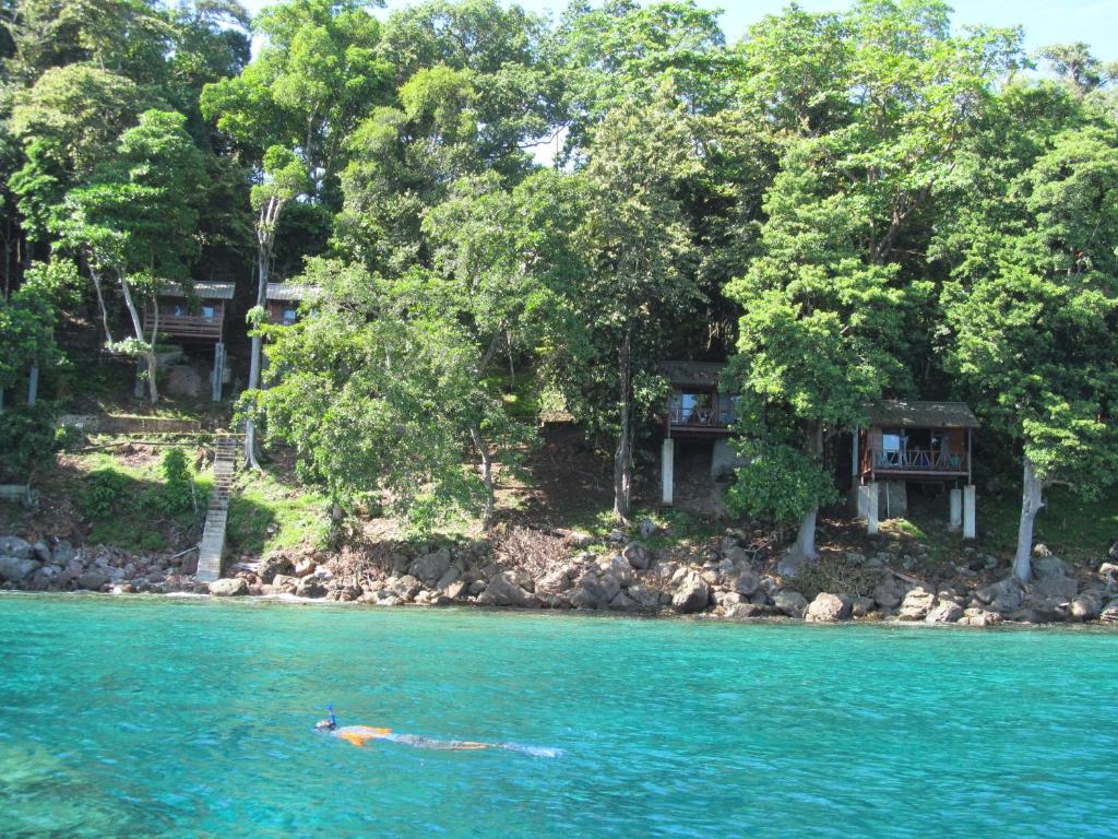 a person in the water in front of a resort at Treetop Guesthouse and Bungalows in Sabong