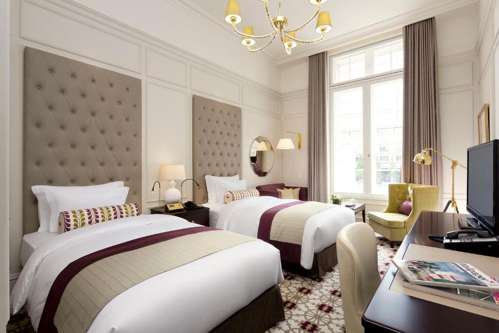 a hotel room with two beds and a desk and a television at The Tokyo Station Hotel in Tokyo