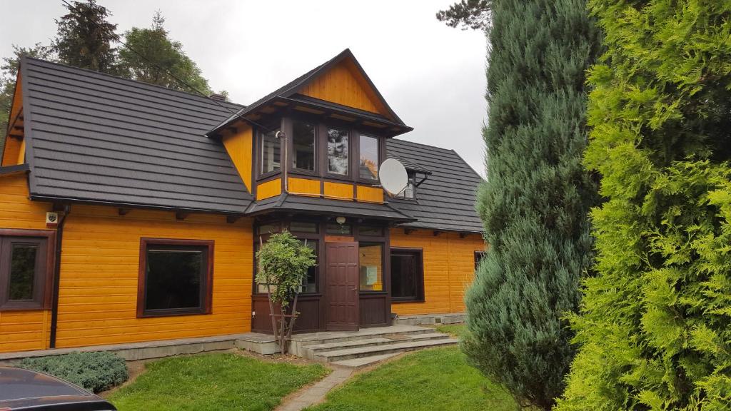 a yellow house with a black roof at Willa Stróża in Myślenice