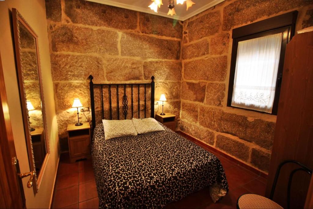 a bedroom with a bed in a stone wall at Casa Balbina in O Grove