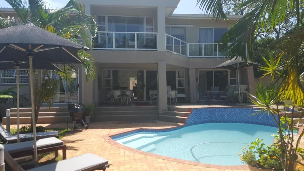 a house with a swimming pool in front of a house at Ridgesea Guest House in Durban