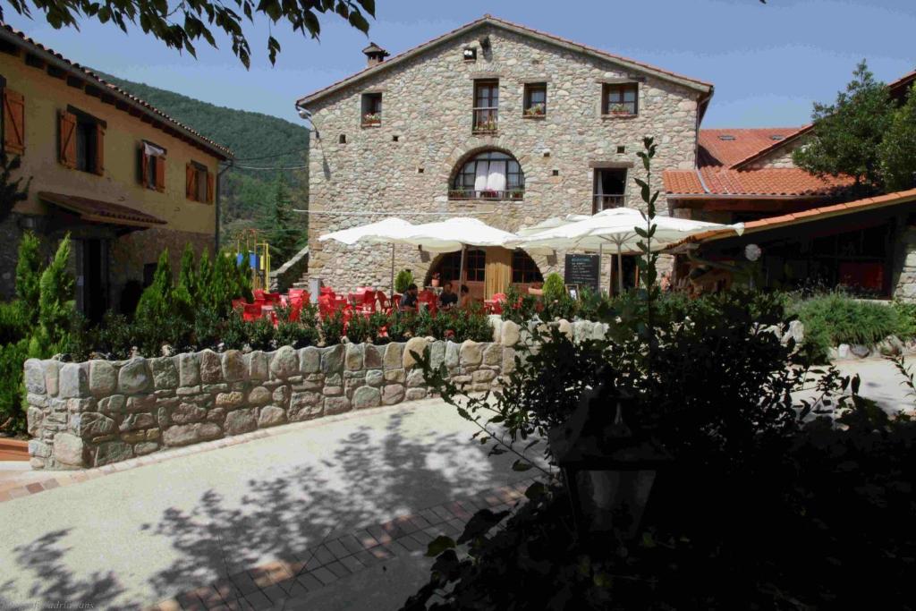 un edificio con una pared de piedra y flores delante de él en Hostal Els Roures, en Camprodon