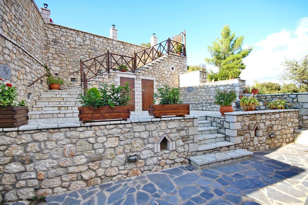 a stone house with potted plants on a stone wall at Thea Valtessinikou in Valtessiniko