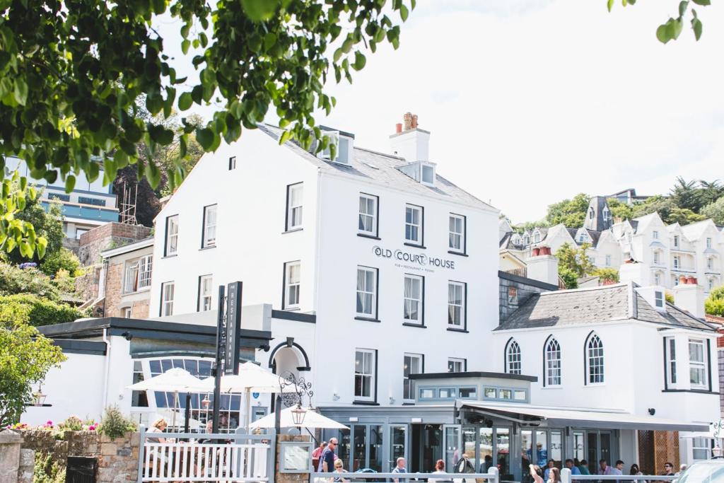 a white building with people sitting outside of it at Old Court House Inn in Saint Aubin