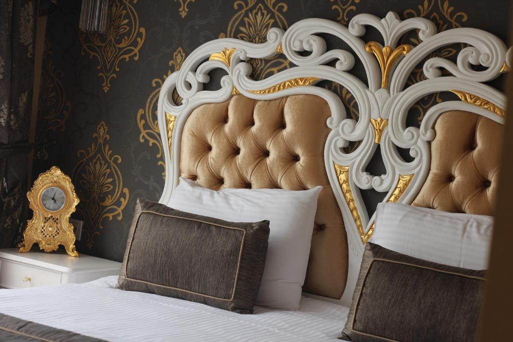 a bedroom with a bed with a gold and white headboard at Gulhane Garden Hotel in Istanbul