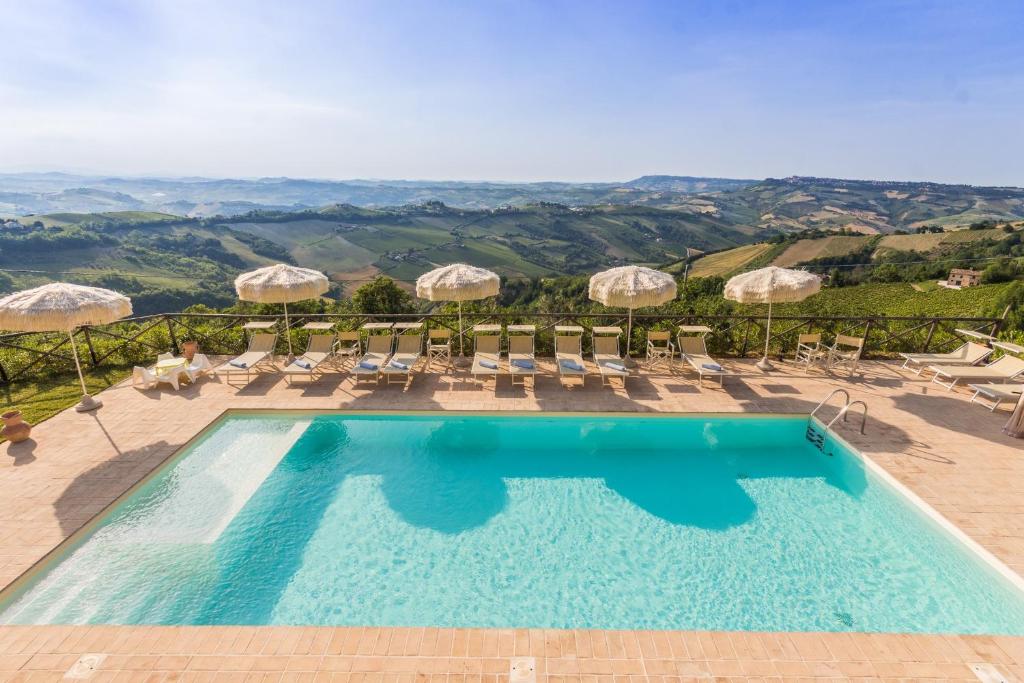 einen Pool mit Stühlen und Sonnenschirmen und Aussicht in der Unterkunft Villa Torre in Ripatransone