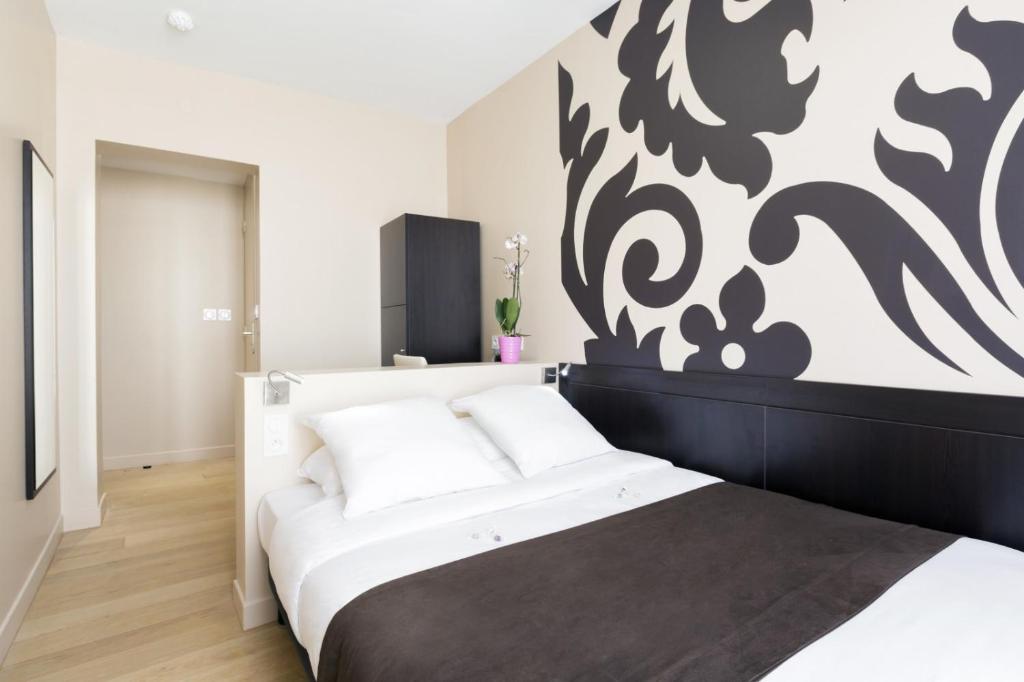 a bedroom with a bed with a black and white wall at Hotel Bastille in Paris