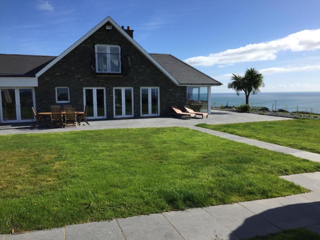 uma casa de tijolos com um pátio e vista para o oceano em Ocean View,Kinsale, Exquisite holiday homes, sleeps 22 em Kinsale