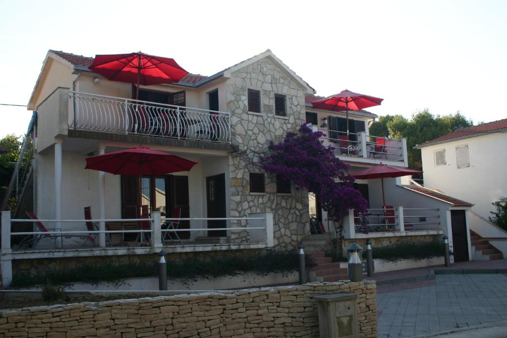 a house with red umbrellas in front of it at The Sea House Apartments in Vis