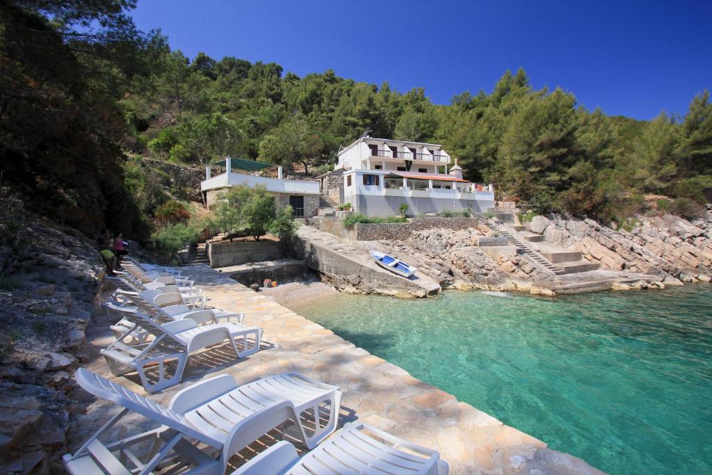 a row of lounge chairs in the water in front of a house at Robinson Monte Cristo in Bogomolje