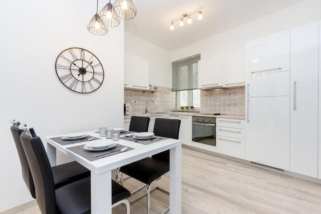 a white kitchen with a white table and chairs at Central Suite Rijeka in Rijeka