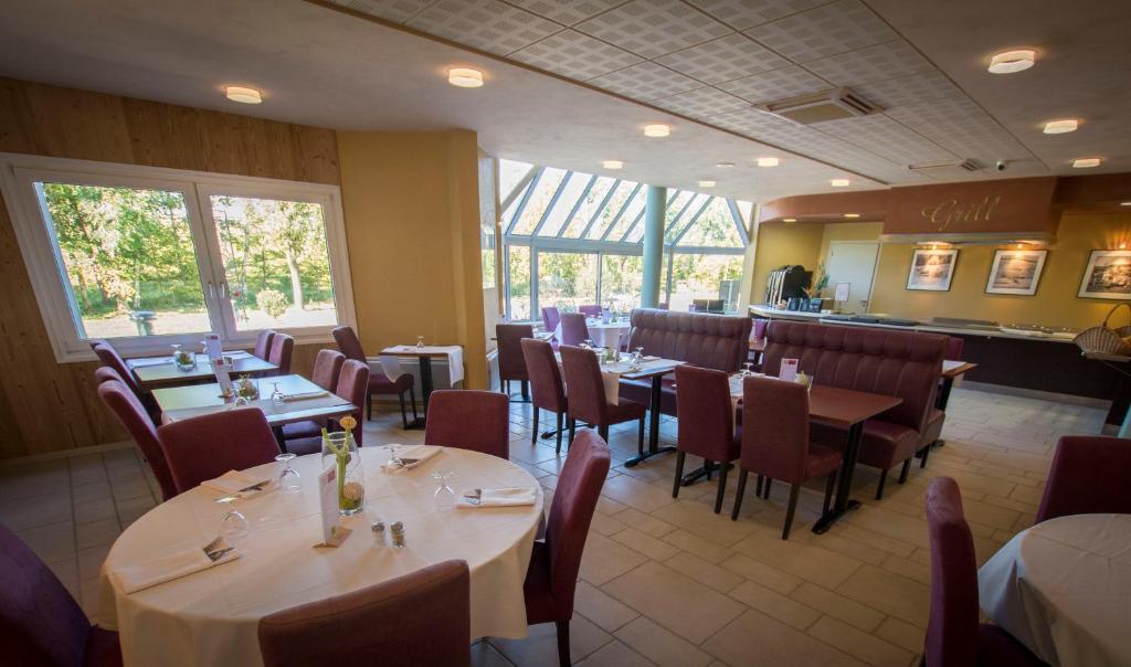 ein Restaurant mit Tischen und Stühlen in einem Zimmer in der Unterkunft Logis Hotel des Cépages in Arbois