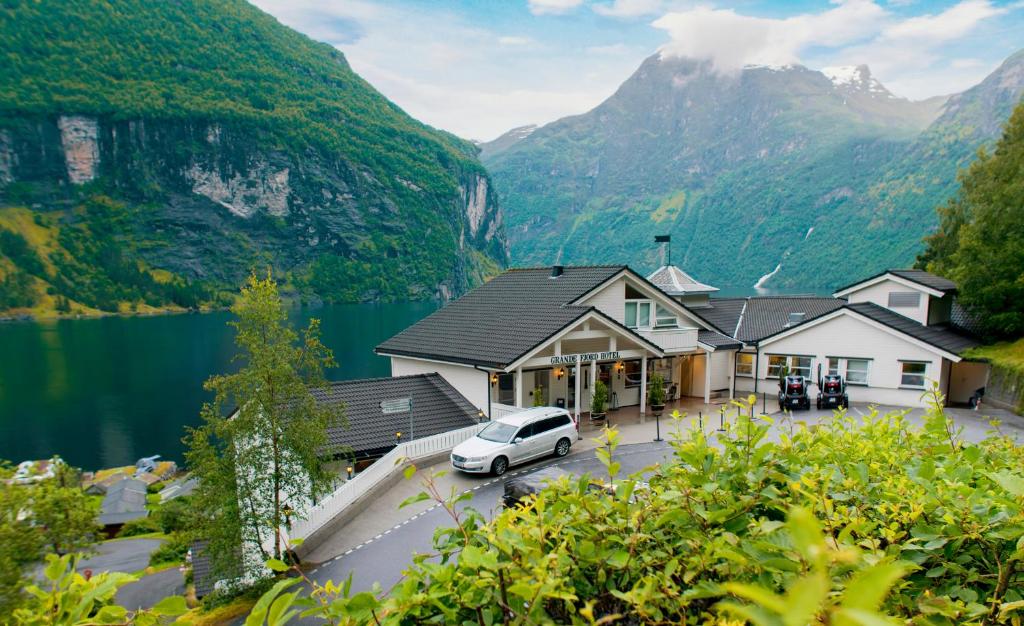 um carro branco estacionado em frente a um edifício com montanhas em Grande Fjord Hotel em Geiranger