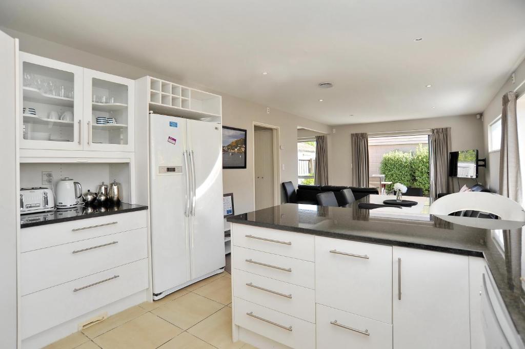 a kitchen with white cabinets and a white refrigerator at Regents 94B - Christchurch Holiday Homes in Christchurch