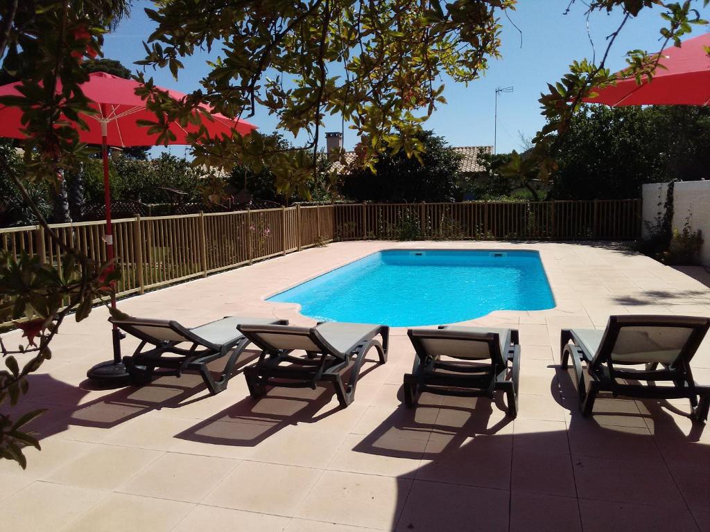 einen Pool mit Liegestühlen, einem Tisch und einem Sonnenschirm in der Unterkunft Les Gites De La Pinede in Balaruc-les-Bains