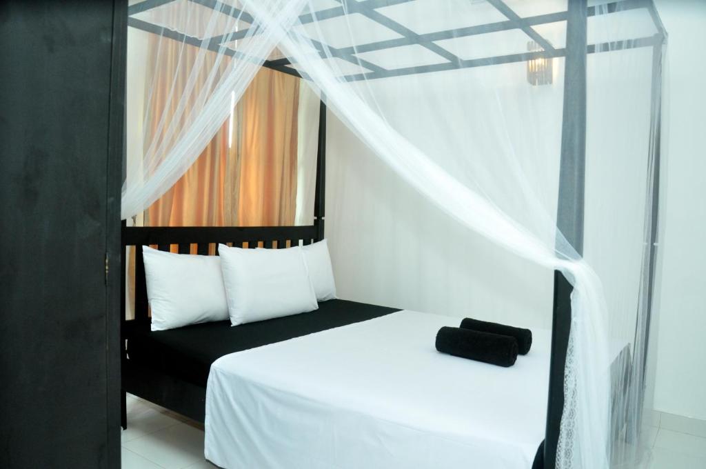 a bedroom with a black and white bed with a canopy at Bon Accord Mirissa in Mirissa