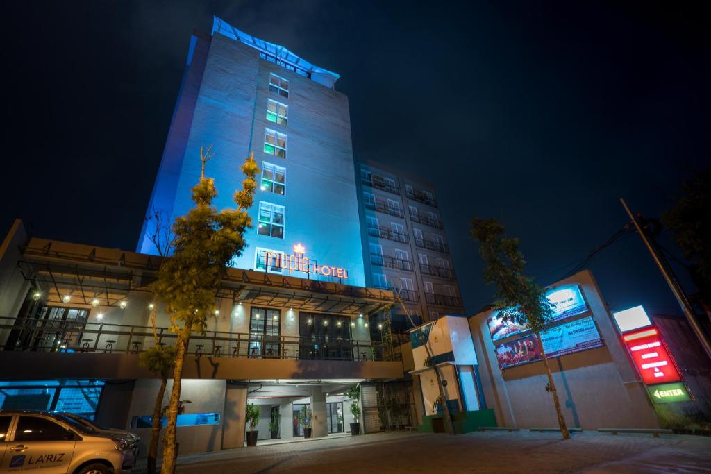 een gebouw dat 's nachts blauw verlicht is bij Maple Hotel Grogol in Jakarta