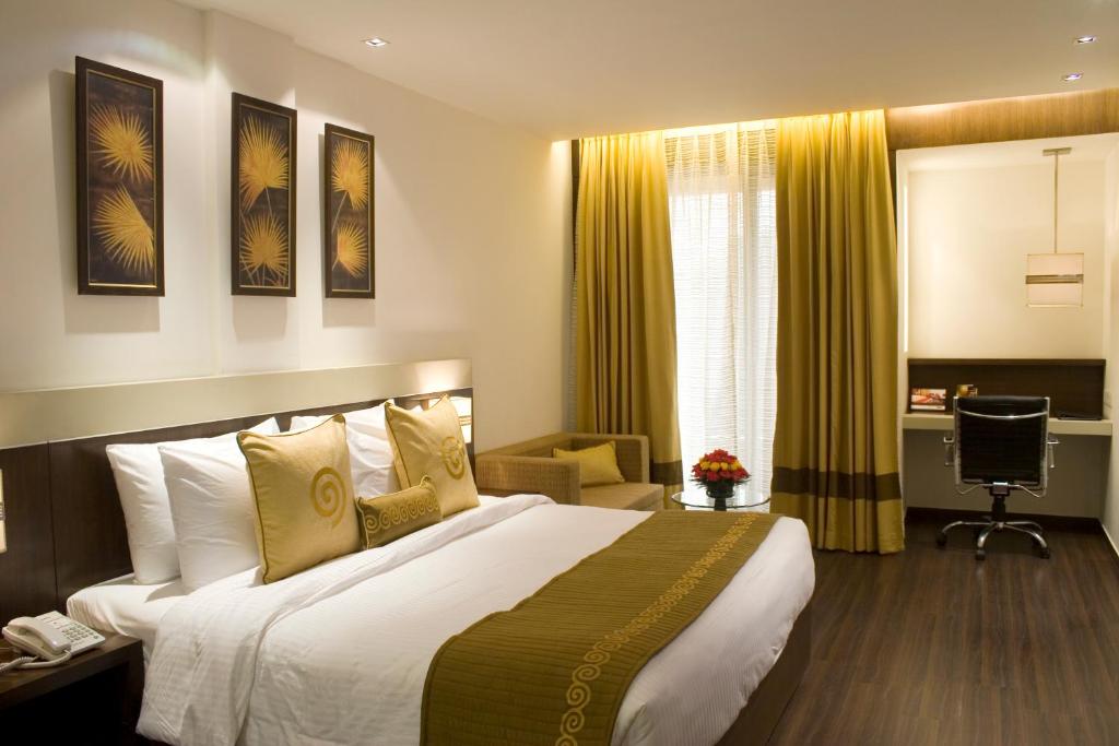 a hotel room with a bed and a desk at Shervani Nehru Place in New Delhi