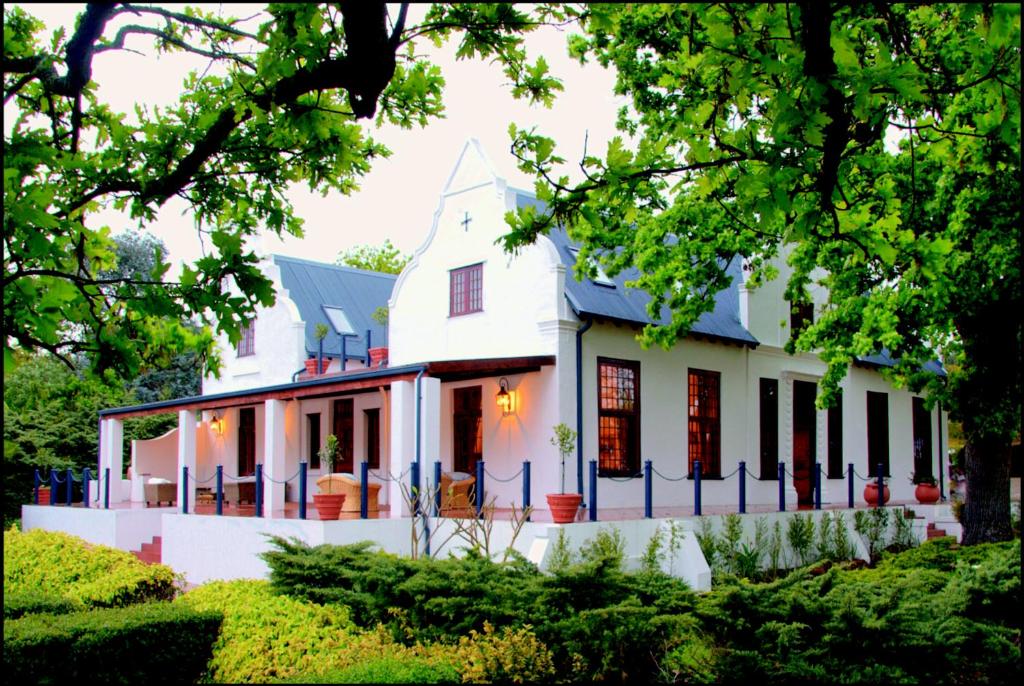 a house that has some trees in front of it at Vredenburg Manor House in Somerset West