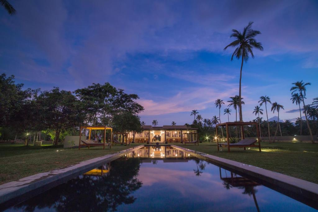 a swimming pool in front of a house at night at Wirdana Resort & Spa in Galle