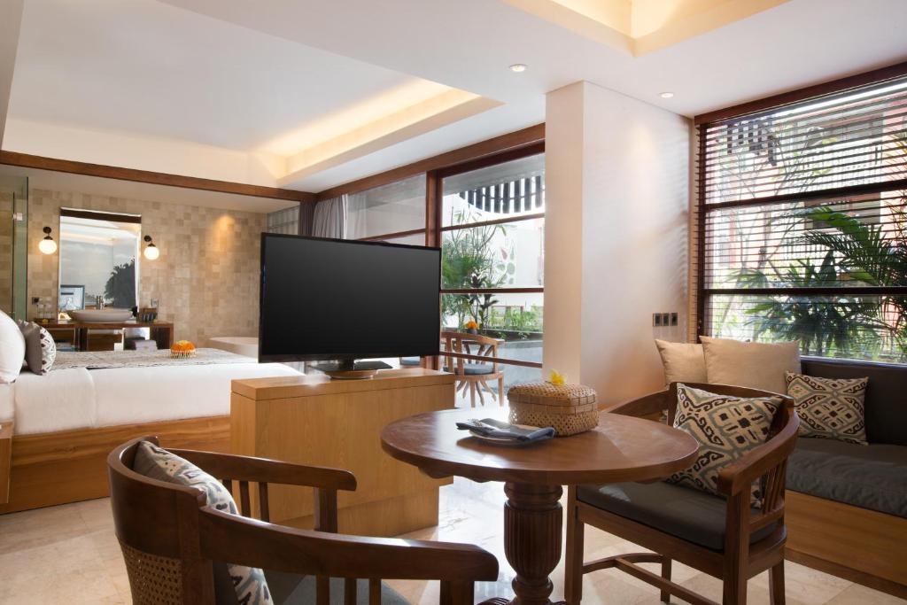 a living room with a television and a couch at Amnaya Resort Kuta in Kuta