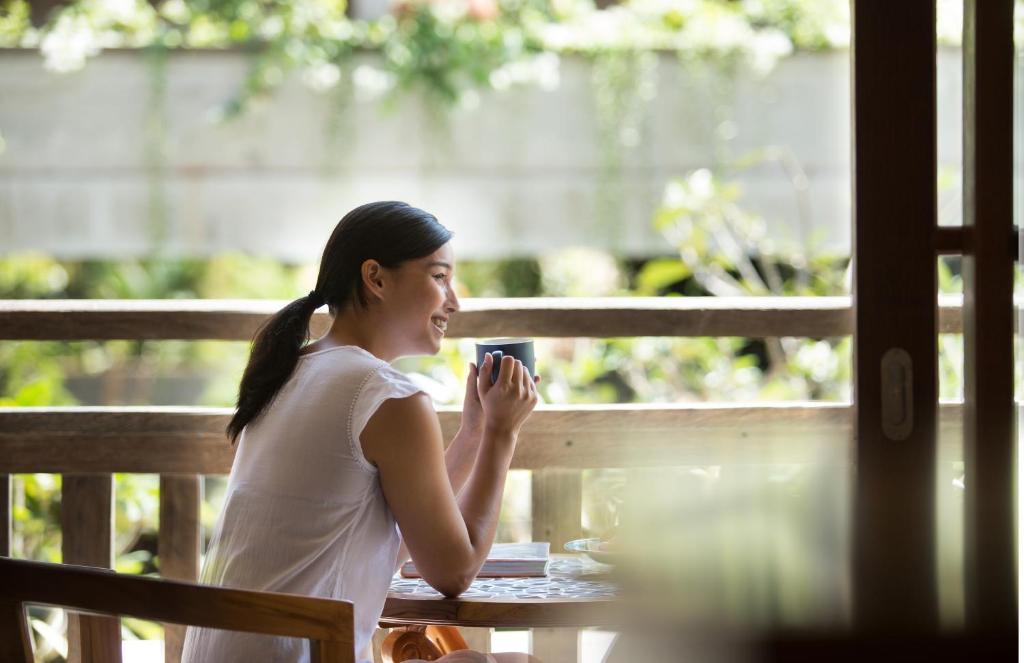 a woman sitting at a table drinking a cup of coffee at Amnaya Resort Kuta in Kuta