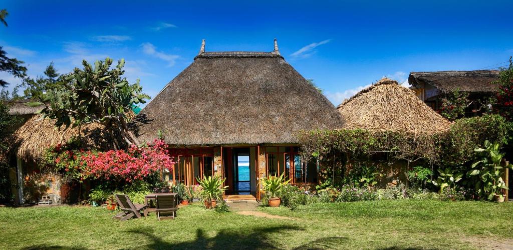 a house with a thatched roof with a garden at Chantauvent Guest House in Blue Bay