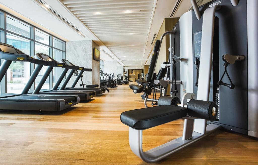 A bright fitness room with treadmills, weight machines, and a long window wall.