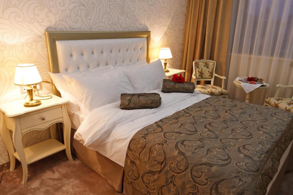a bedroom with a large bed and a table with lamps at Hotel Roman by Dumbrava Business Resort in Roman
