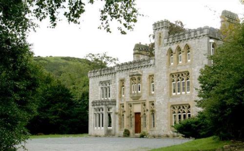 a large stone building with trees in front of it at Ffarm Country House in Abergele