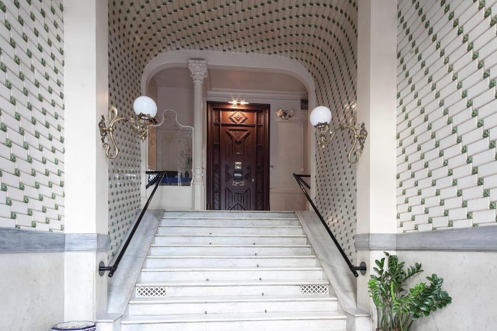 a hallway with a staircase leading to a wooden door at Apartments Barcelona & Home Deco Eixample in Barcelona