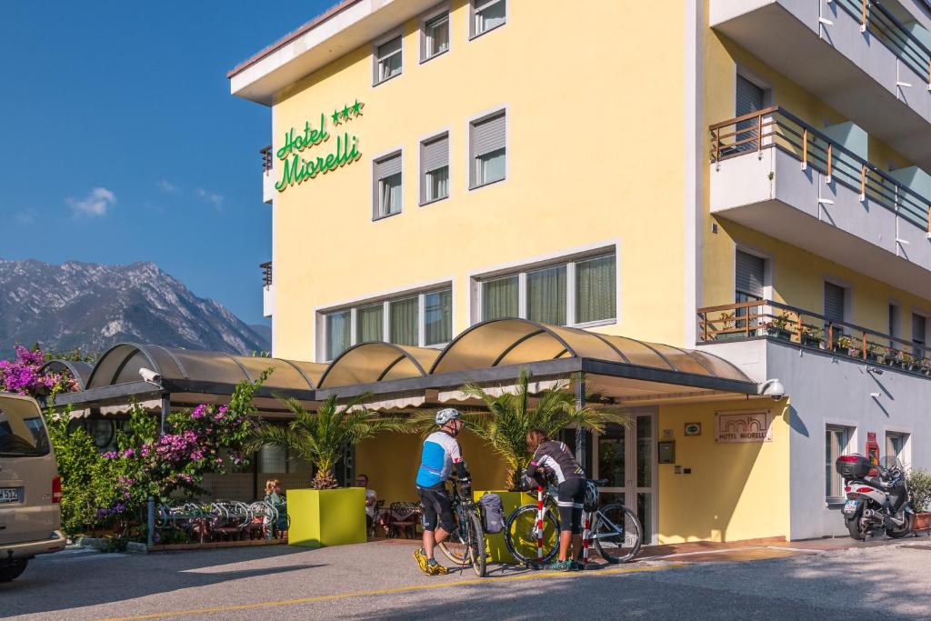 2 persone in bicicletta di fronte a un hotel di Hotel Miorelli a Torbole