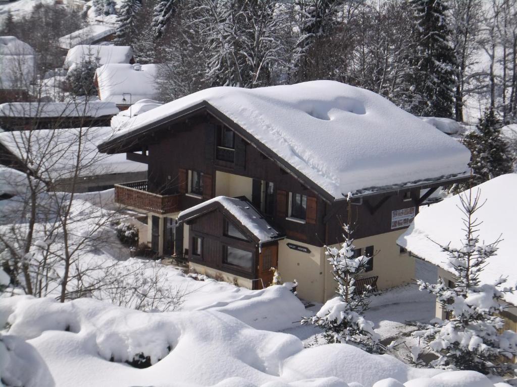 una casa cubierta de nieve con nieve en Chalet Aventure B&B Les Gets en Les Gets