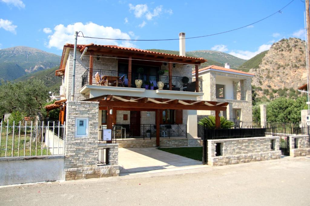 uma casa com uma varanda com montanhas ao fundo em Amaryllis Holiday Home em Agios Spiridon Fokidas