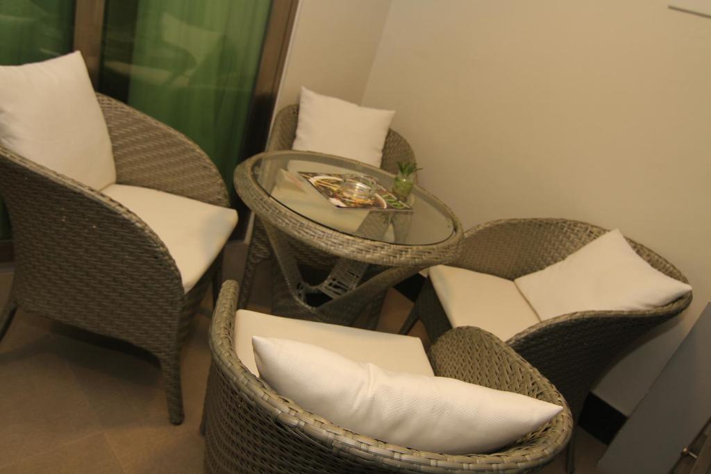 two wicker chairs and a glass table with a tableasteryasteryasteryasteryastery at Eloisa Royal Suites in Mactan
