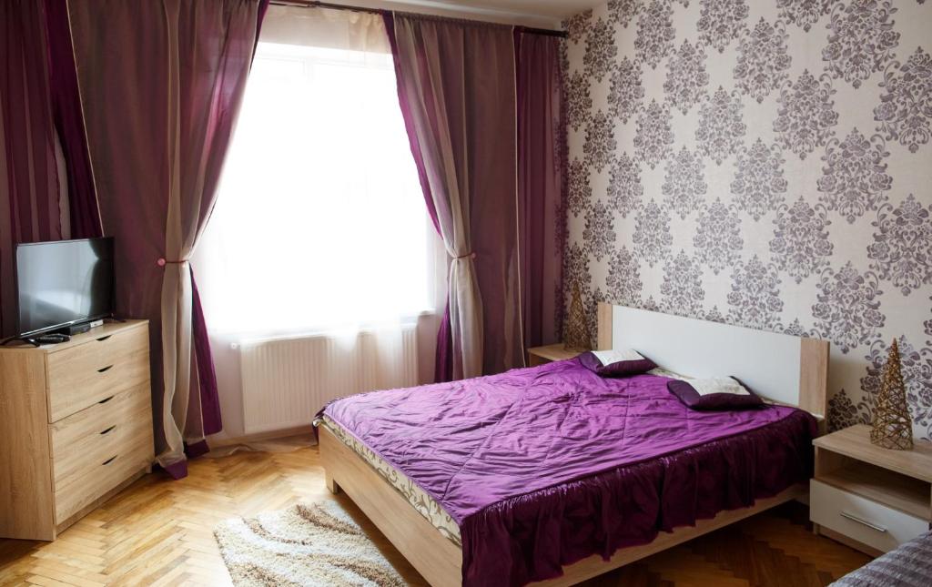 リヴィウにあるApartment on Tyktoraのベッドルーム(紫色のベッド1台、窓付)