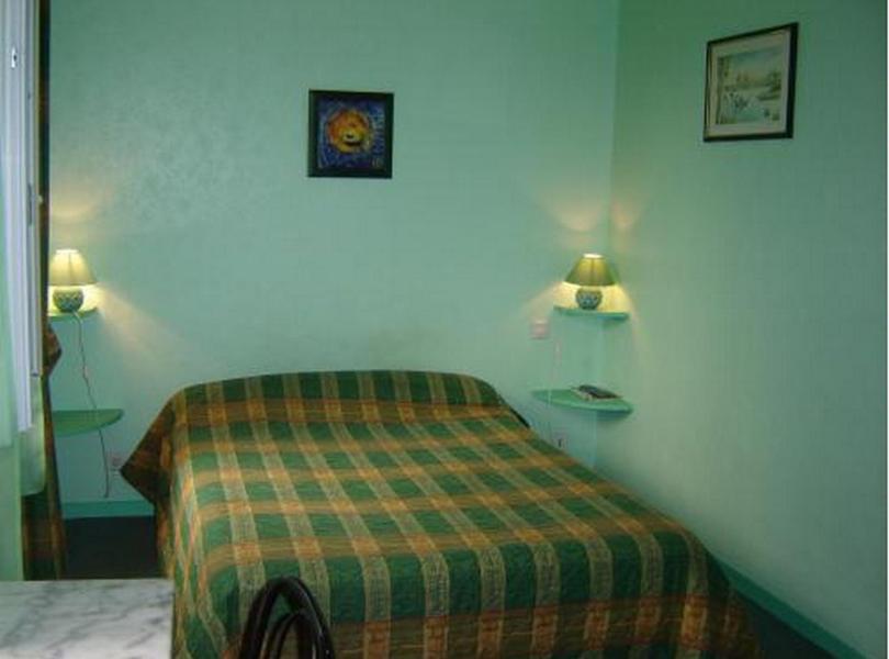 a bedroom with a bed and two lamps on the wall at Hotel Restaurant du Lion d'Or in Château-Chinon