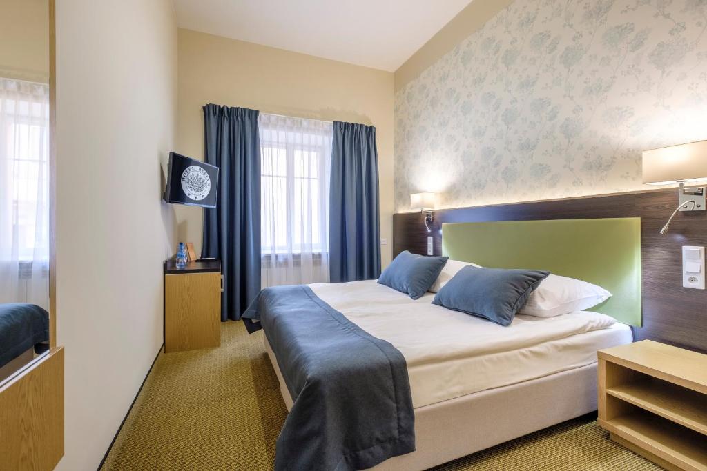 a hotel room with a large bed with blue pillows at Hotel Reytan in Warsaw