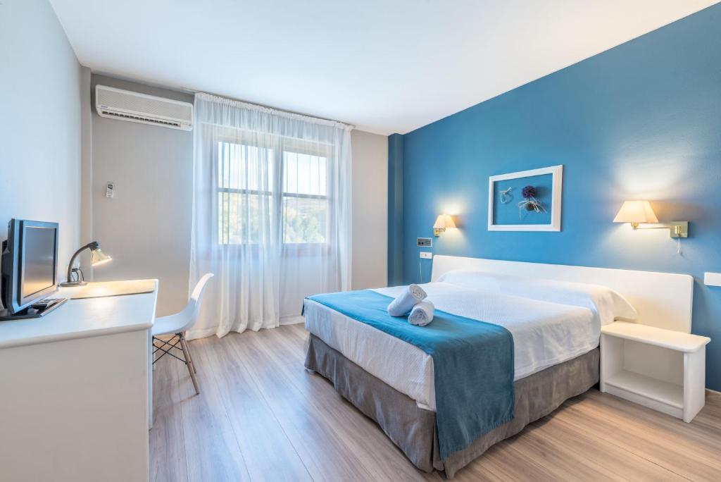 プエンテ・ラ・レイナにあるHotel Jakueの大きなベッドとデスクが備わるホテルルームです。