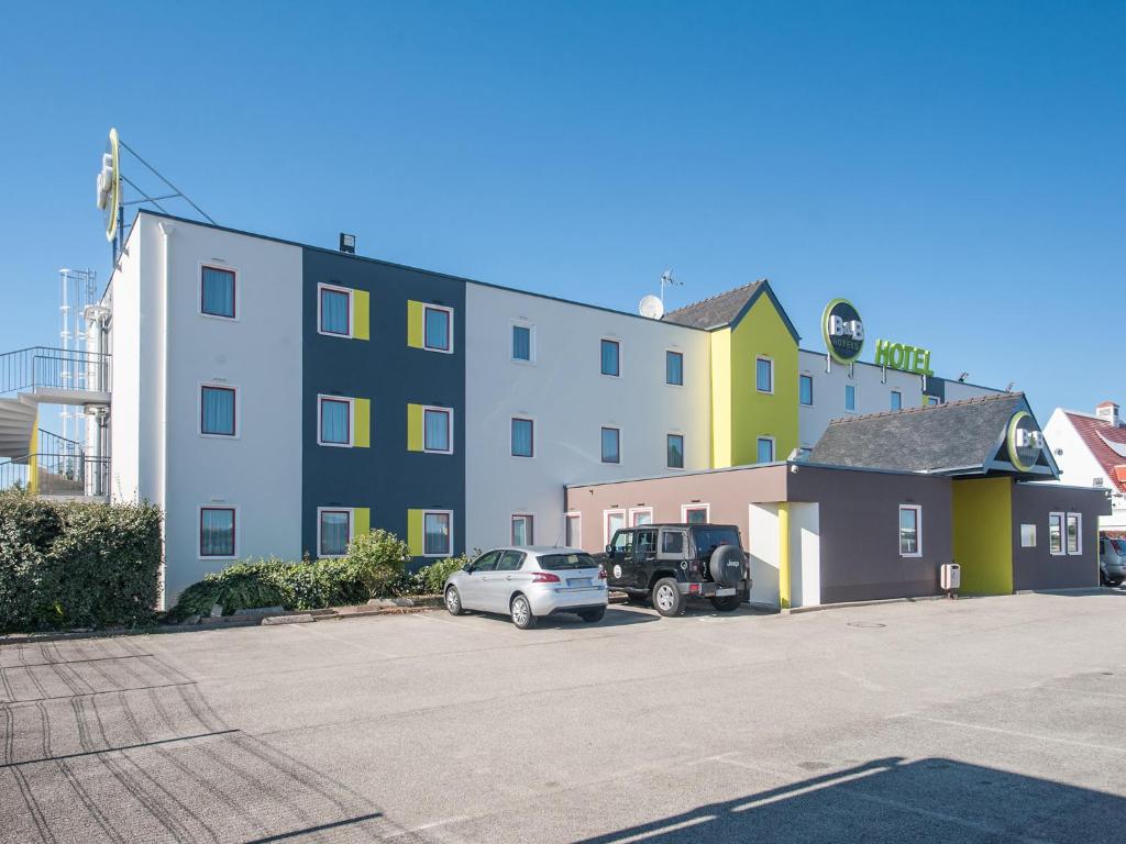 un bâtiment avec une voiture garée sur un parking dans l'établissement B&B HOTEL Lorient Caudan, à Caudan