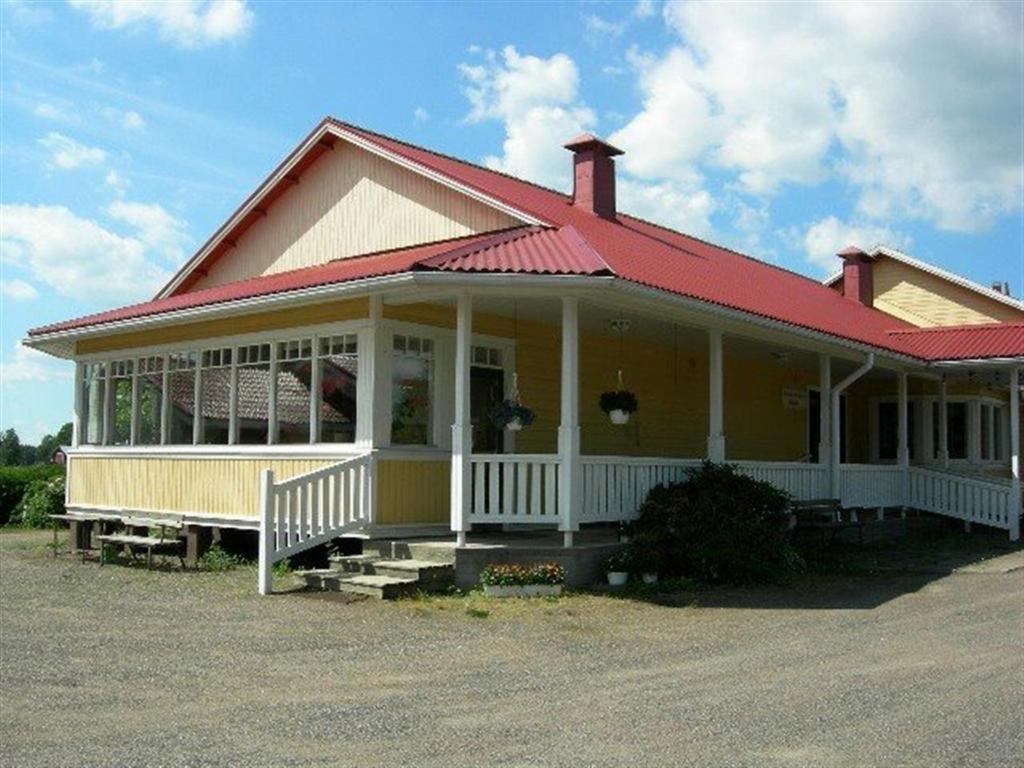 Majatalo Myötätuuli في Pitkäjärvi: منزل اصفر كبير بسقف احمر