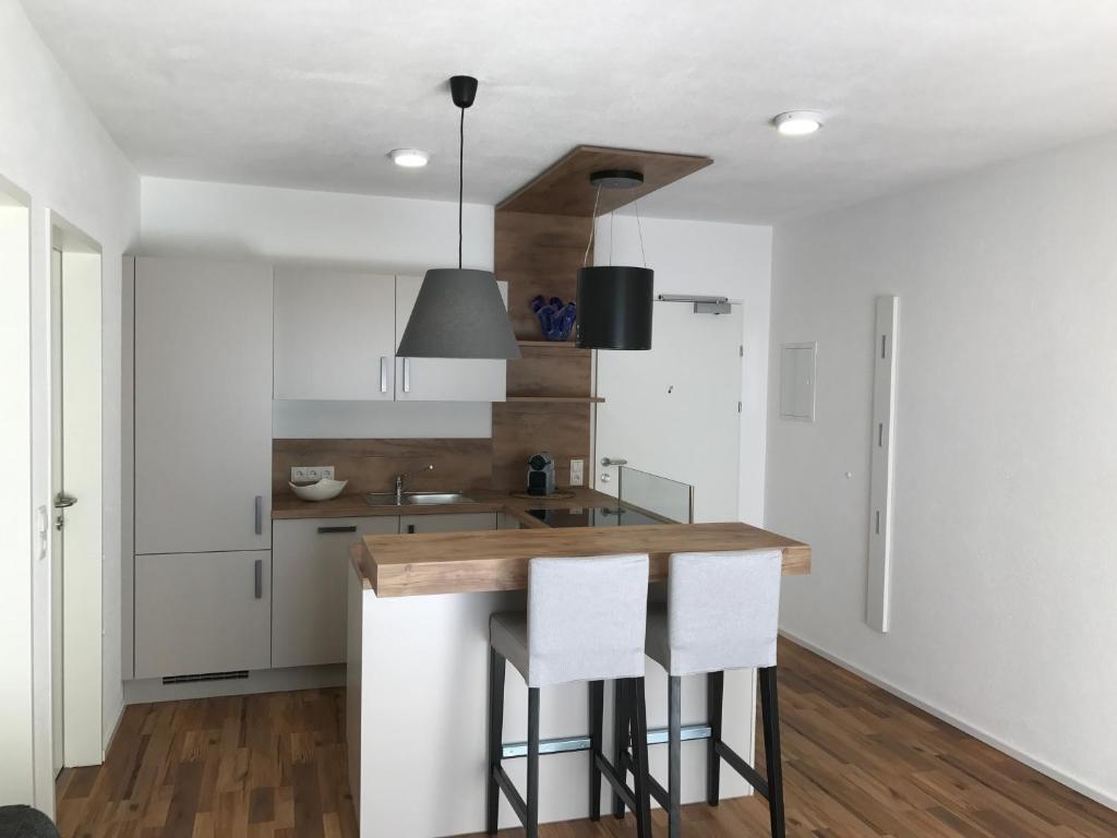 a kitchen with white cabinets and a counter with stools at Appartement Tirolina in Innsbruck