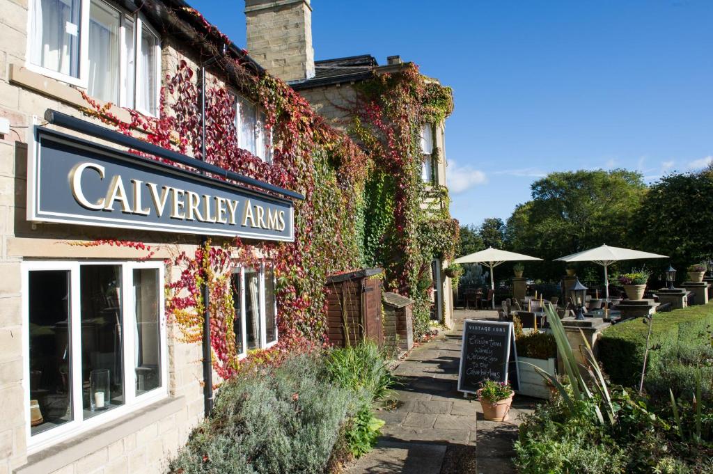 The Calverley Arms by Innkeeper's Collection في بودسي: مبنى مغطى في اللبلاب مع وضع علامة عليه