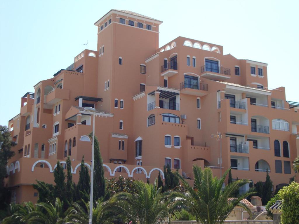 un gran edificio de naranjos con palmeras delante en Fenix Apartamentos, en Roquetas de Mar