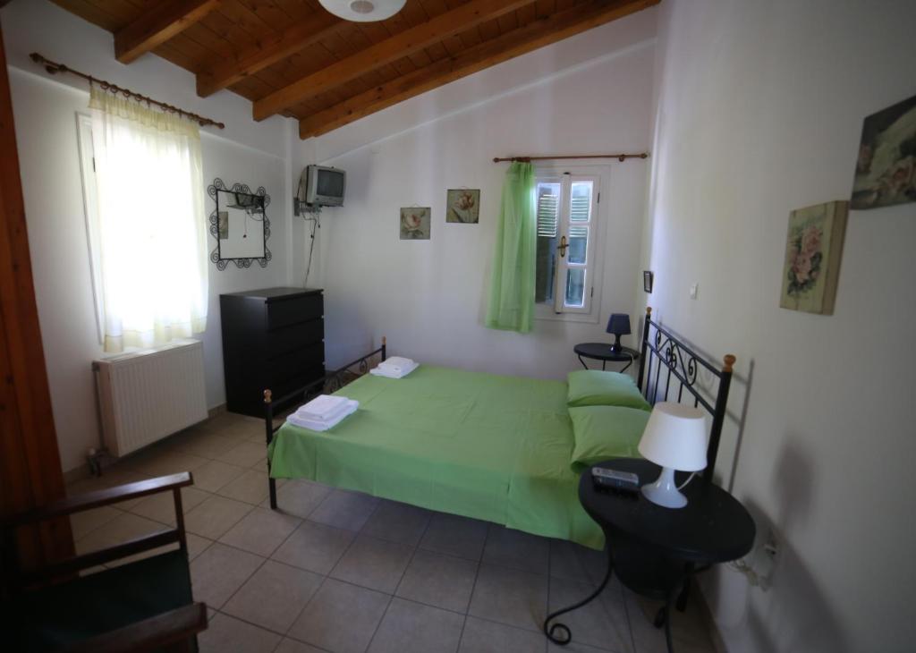 1 dormitorio con 1 cama verde y TV en Studios Argyri en Agios Kirykos