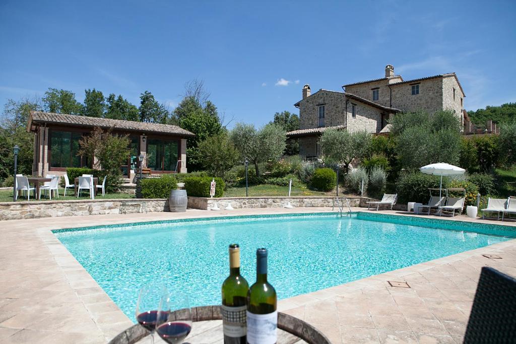 a pool with two bottles of wine next to a house at Re Artù Assisi Country Lifestyle in Assisi